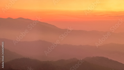 Mountain view evening of Top hill around with soft fog with yellow and red sun light in the sky background, sunset at Huai Nam Dang National Park, Chiang Mai, Thailand.