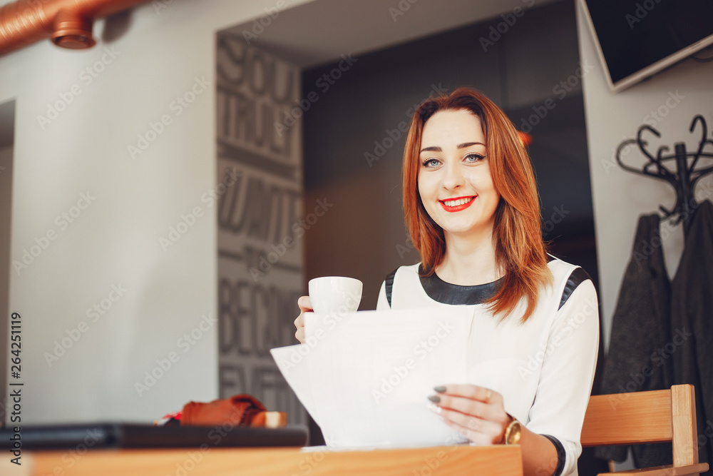 Beautiful girl in the office.The woman is sitting at the table. Girl drinks coffee