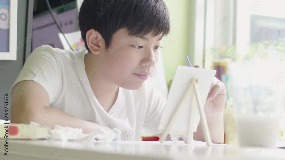 Young asian boy painting water color at home with smile face, Young asian boy painting water color at home with smile face,