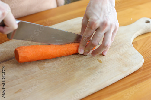 woman cutting carrot on wooden board