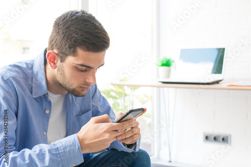 young man or teenager with mobile phone at home