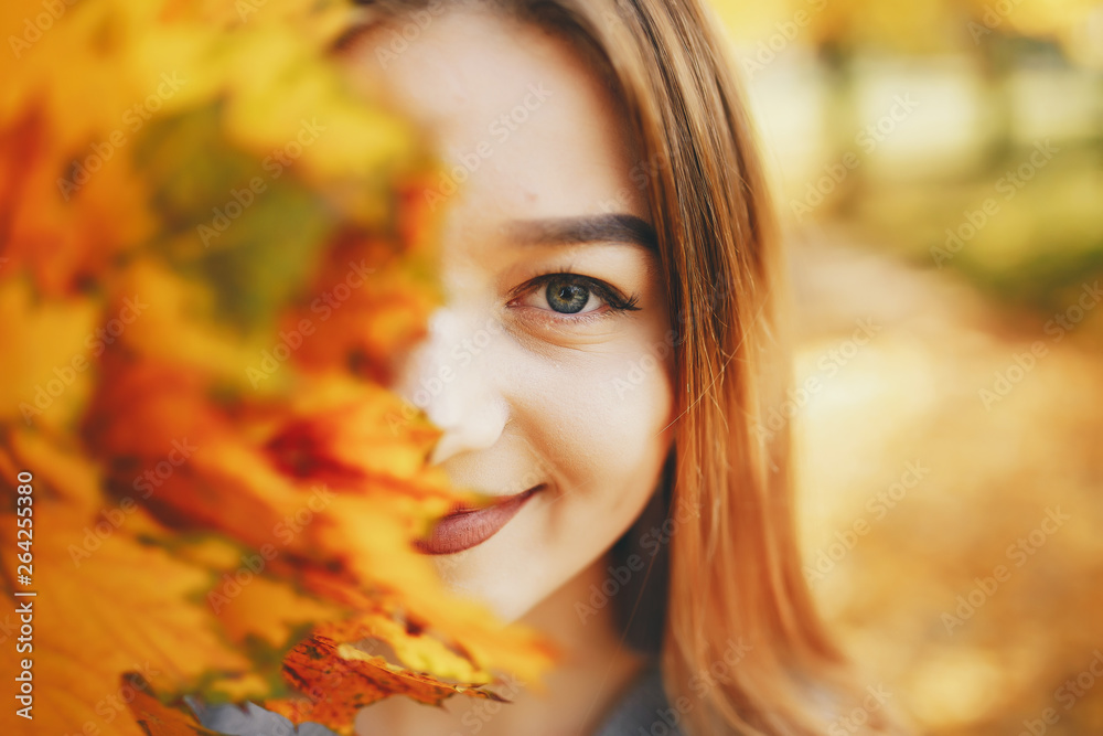 pretty cute girl with make up, dressed in black dress standing in a autumn park keeps the leaves near the face pretty cute girl with make up, dressed in black dress standing in a autumn park keeps the leaves near the face
