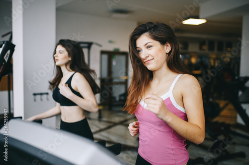 Beautiful girls in the gym. Two oladies are engaged in sports. Women on a treadmill