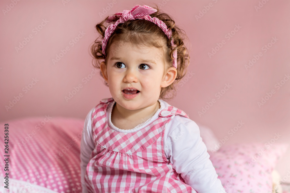 Portrait of Little Happy Girl with Curly Hair and Pink Dress.Close up of a Happy Smiling Child in a Pink Room Portrait of Little Happy Girl with Curly Hair and Pink Dress.Close up of a Happy Smiling Child in a Pink Room