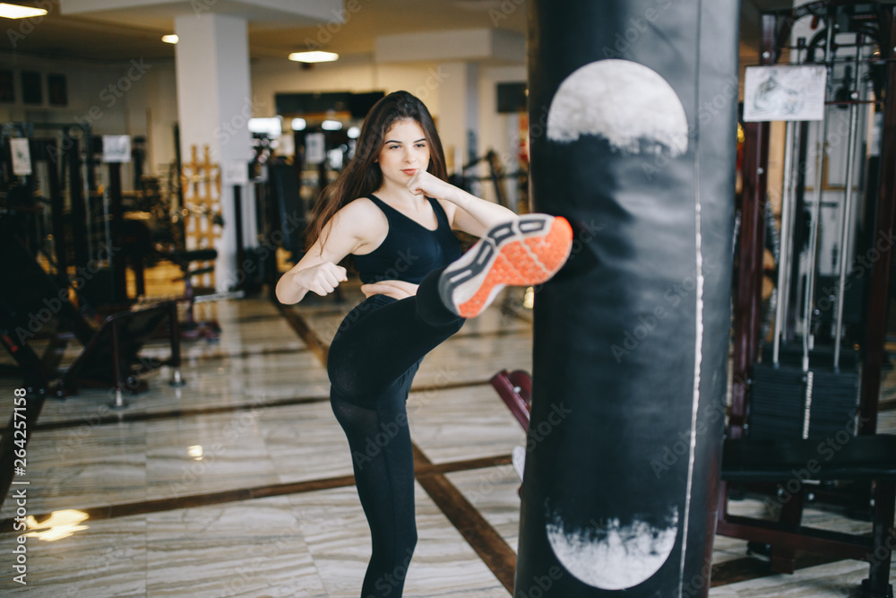 Beautiful girl in the gym. A woman performs exercises. The girl is boxing