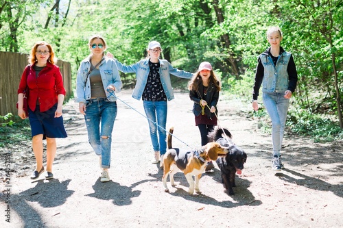 Canvas Print Mothers with daughters walking with two dogs on leashes on fores