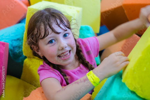 The child is having fun in the children's room with colorful cubes. Portrait of a little beautiful girl