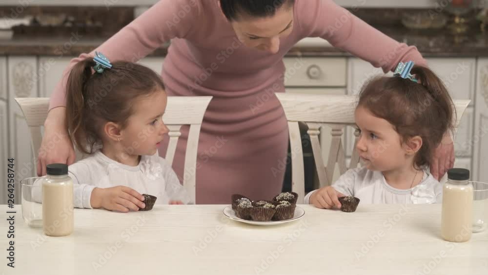 Beautiful twin girls tasting healthy and nutritious dessert. Homemade candies with exotic dried fruits and nuts. Healthy lifestyle concept Beautiful twin girls tasting healthy and nutritious dessert. Homemade candies with exotic dried fruits and nuts. Healthy lifestyle concept