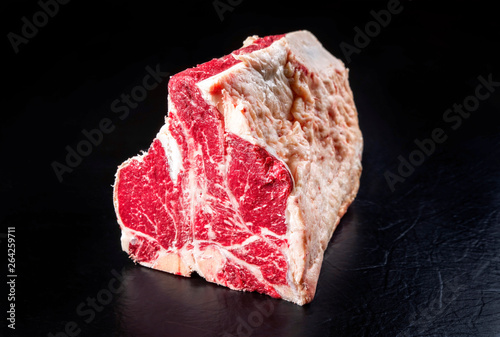 Raw dry aged wagyu porterhouse beef block as closeup on black background with copy space
