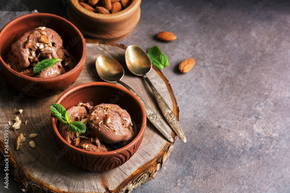 Fototapeta premium Homemade chocolate ice cream with almonds and mint leaves on a dark rustic background. Selective focus, copy space