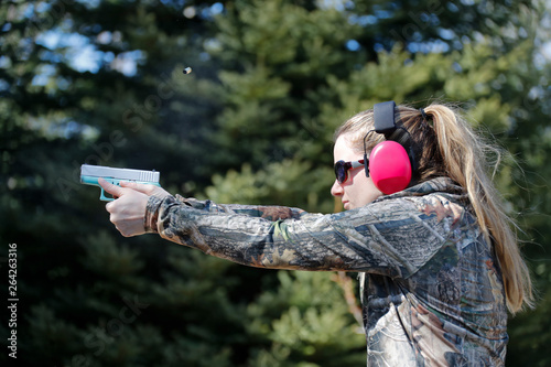 Canvas Print A woman shooting a handgun and the ejected cartridge case in the air
