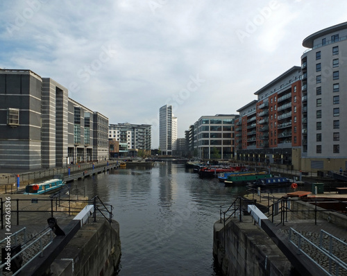 a view of leeds dock from the lock gates showing waterside developments offices and apartment buildings with houseboats moored in the water