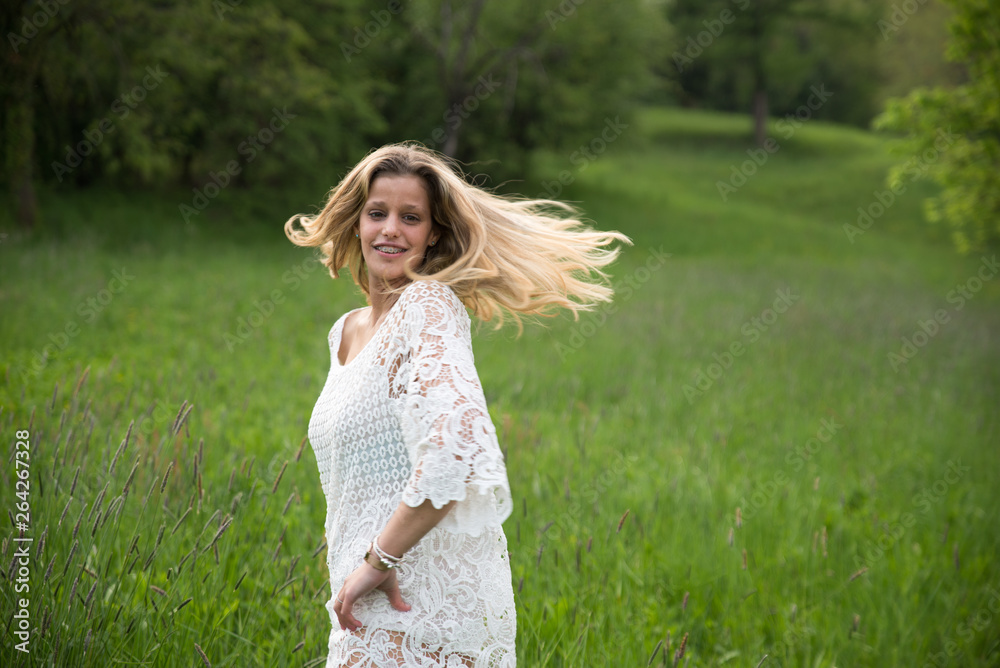 Young happy caucasian woman smiling in a meadow full of flowers. Nature and happiness concepts Young happy caucasian woman smiling in a meadow full of flowers. Nature and happiness concepts