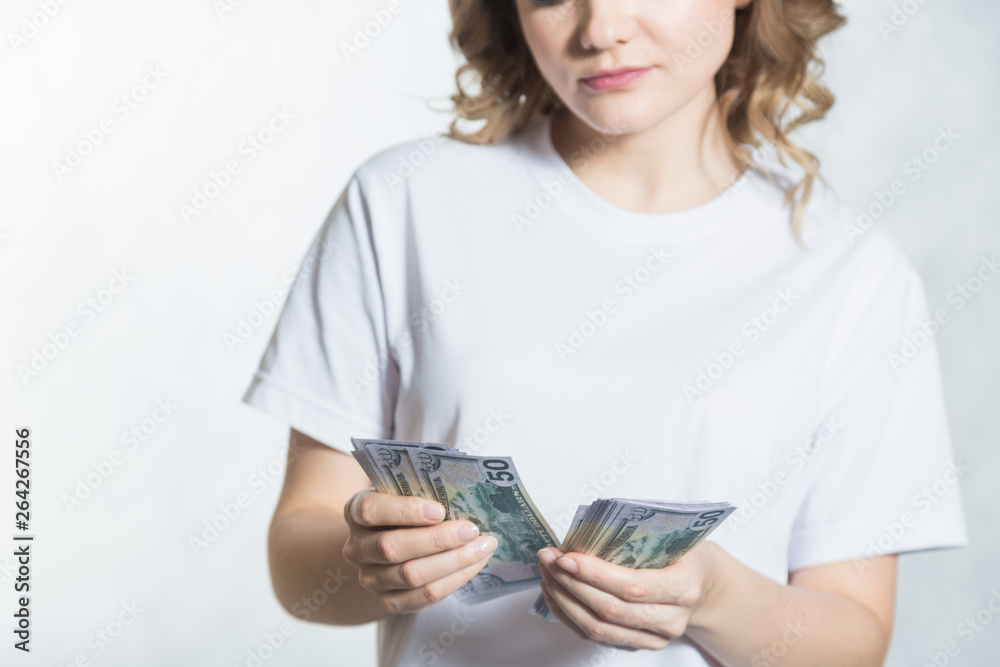 Pensive young woman counts us dollar money over white background. Pensive young woman counts us dollar money over white background.