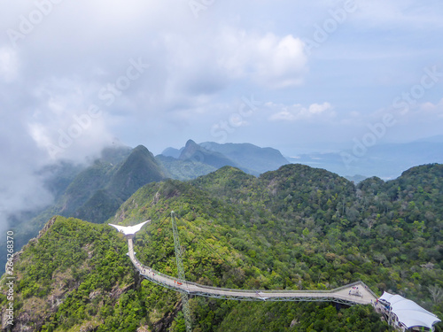 Langkawi Sky Bridge located 660 metres above sea level at the peak of Gunung Mat Cincang on Pulau Langkawi. Lots of peaks around the bridge. Clouds covering the sky completely.