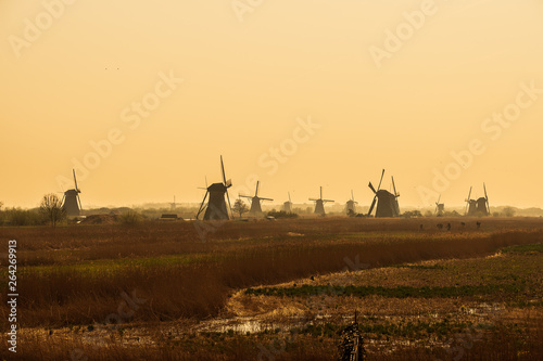 Silhouette of old windmills on a field © Lari
