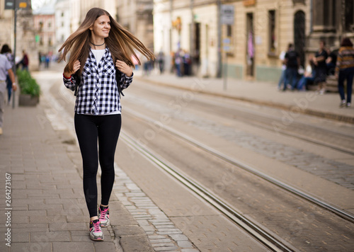 Young tourist woman with backpack walk by street in old europe city, summer fashion style