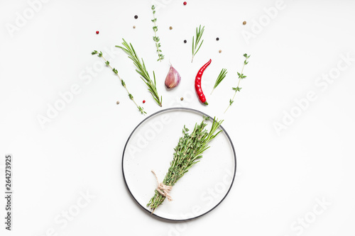 Fototapeta Naklejka Na Ścianę i Meble -  Empty plate with greens herbs and spices around