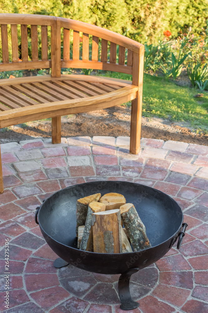 Feuerschale im Garten als gemütlicher Platz der Erholung mit Holzbank