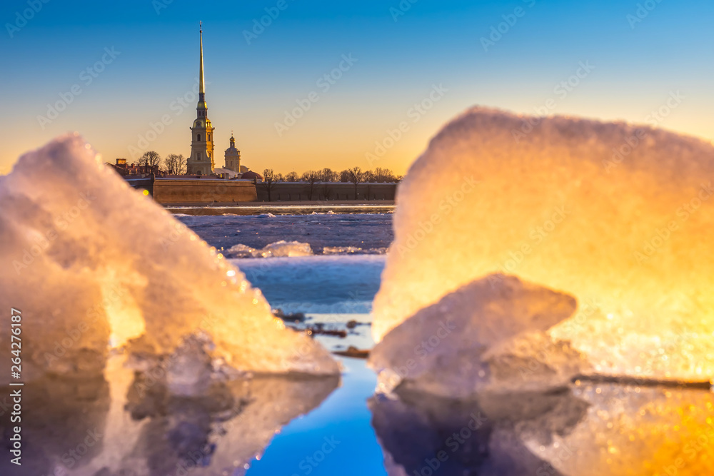 Fototapeta premium Saint-Petersburg. Russia. View of the Peter and Paul fortress through the ice on the Neva. Spring ice melts on the Neva river. Ice drift in Petersburg. Early morning Petersburg. Russian museums.