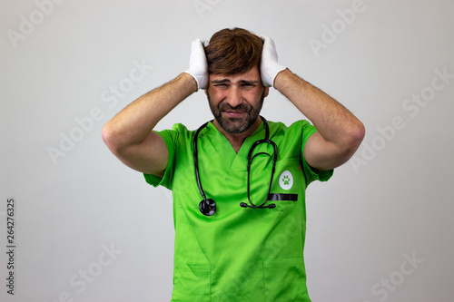 Portrait of male veterinary doctor in green uniform with brown hair stressed, looking at the camera. Isolated on white background.