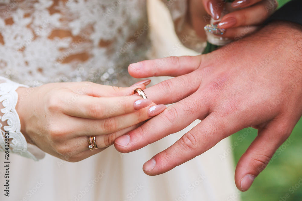 bride wears a ring on the hand of the groom on wedding ceremony outdoor