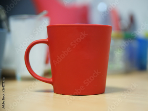 Red cup with handle standing on a beige table