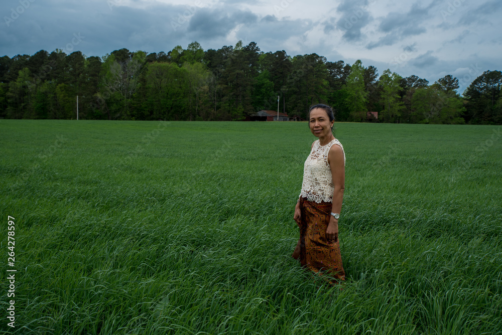 Asian woman in field surrounded by grass Asian woman in field surrounded by grass