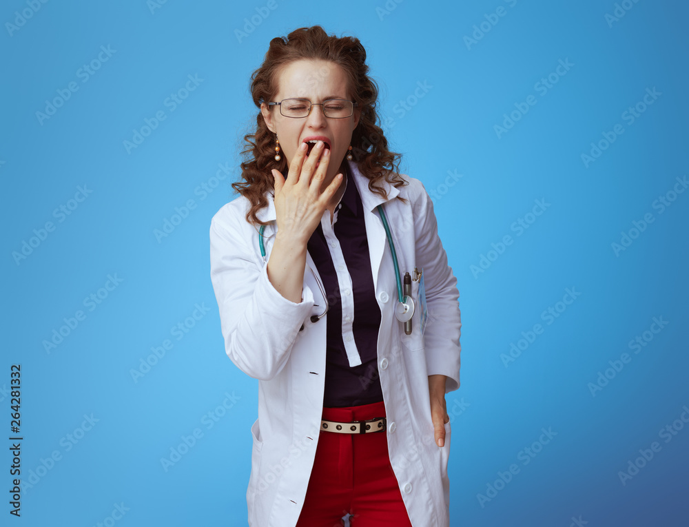 elegant medical practitioner woman yawing on blue elegant medical practitioner woman yawing on blue