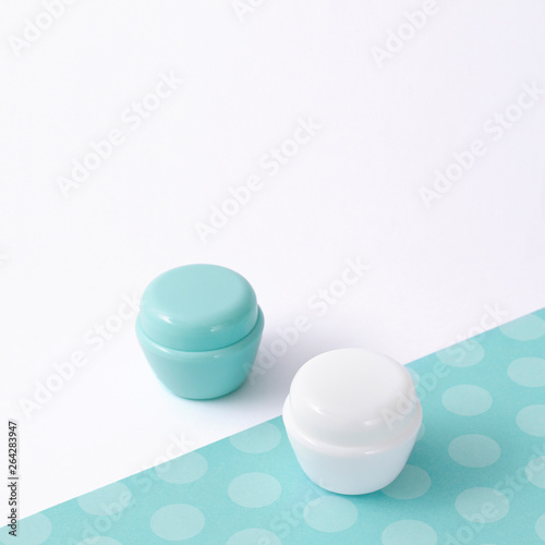 White and turquoise cosmetic bottle containers with decor  on white background top view flat lay.