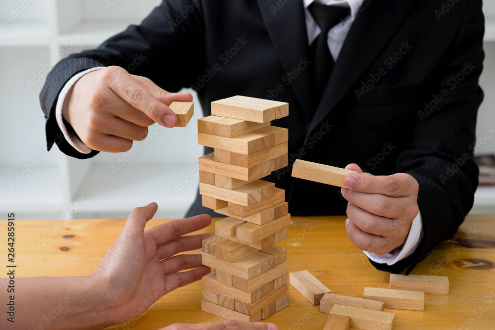 Businessmen picking wood blocks to fill the missing wood blocks and protect wood blocks to fail. Growing business concept. Businessmen picking wood blocks to fill the missing wood blocks and protect wood blocks to fail. Growing business concept.