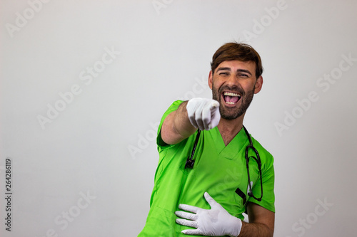 Portrait of male veterinary doctor in green uniform with brown hair pointing while laughing, looking at the camera. Isolated on white background.