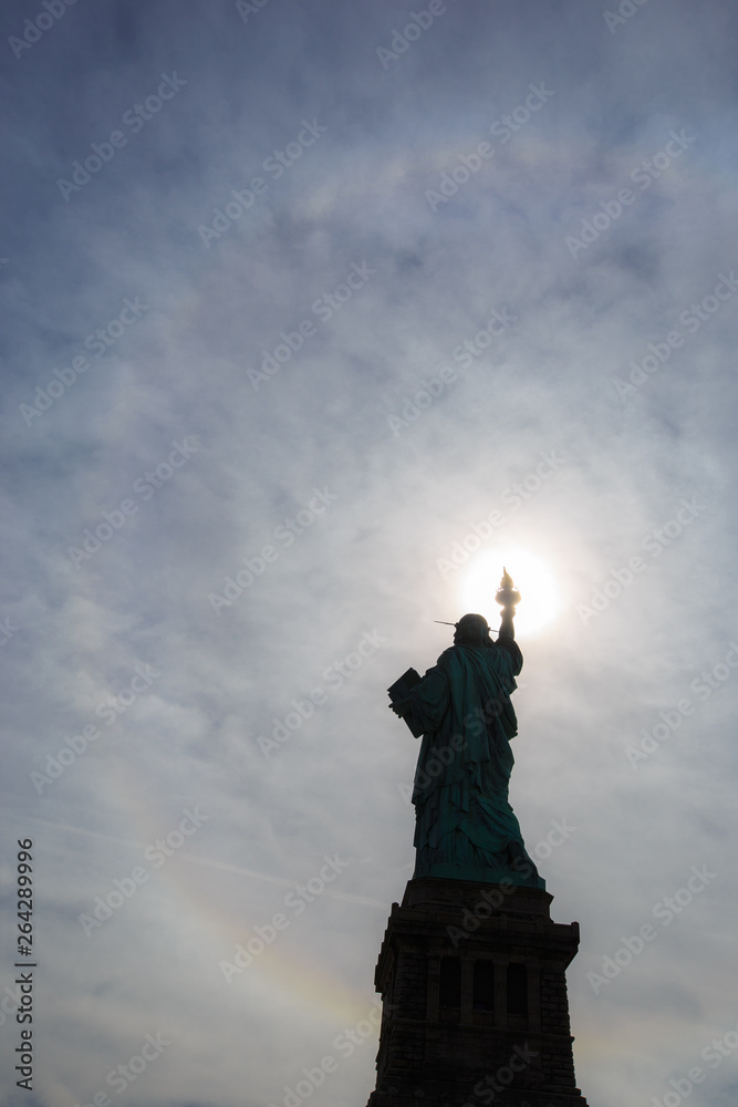 Silhouette of Statue of Liberty in New York with rainbow halo 