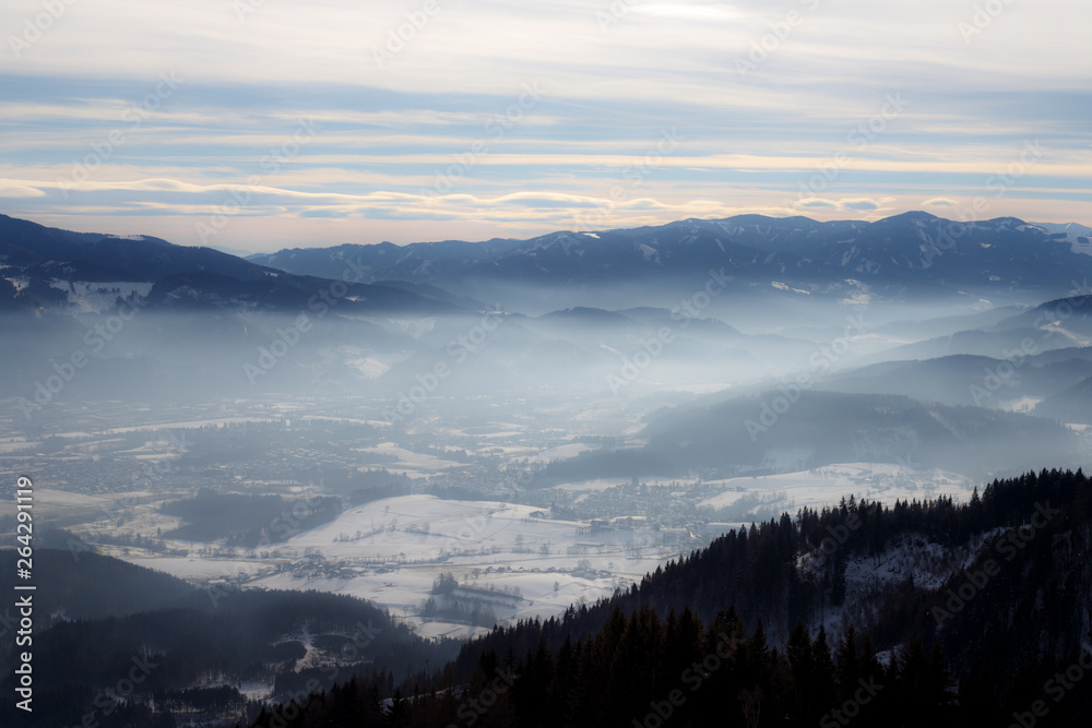 Alpine winter panorama with a misty valley with clouds and mountains foggy winter sky in the european alps