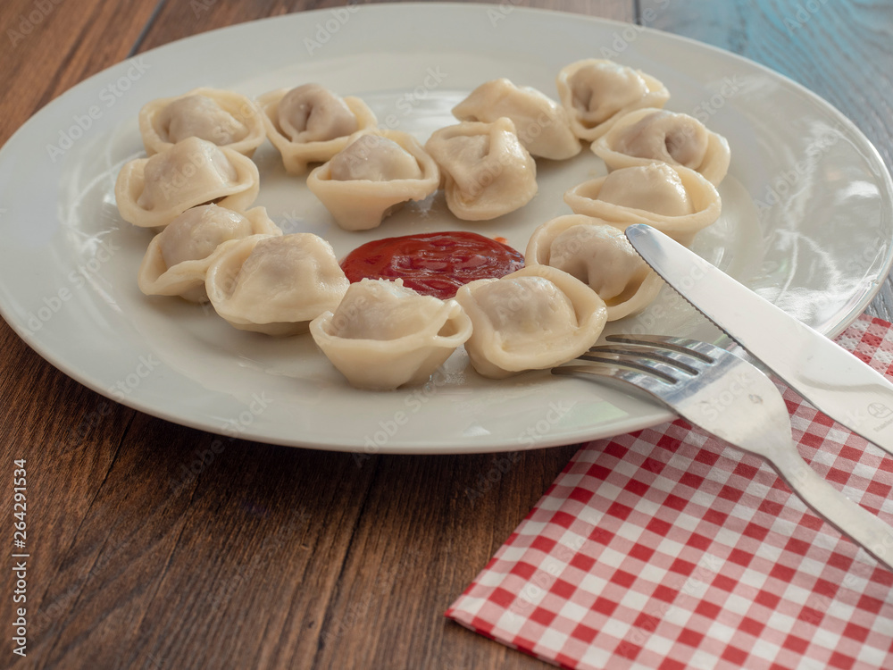 Plate with russian dumplings on a white plate, Wooden table, Fork and knife. Plate with russian dumplings on a white plate, Wooden table, Fork and knife.