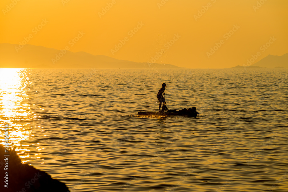Silhouette of young couple on stand up paddle board. Active vacation, beach life. Silhouette of young couple on stand up paddle board. Active vacation, beach life.