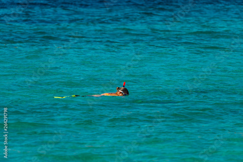 Vacation tourist, young person, snorkeling in paradise clear water. Snorkeler in crystalline waters . Turquoise sea background.