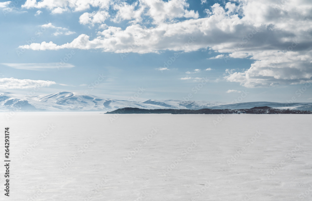frozen lake with surrounding snow covered rocky mountains 