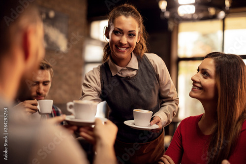 Happy waitress serving coffee to her guest in a cafe 