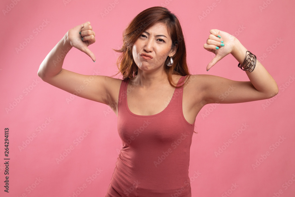 Unhappy Asian girl show thumbs down with both hands. Unhappy Asian girl show thumbs down with both hands.