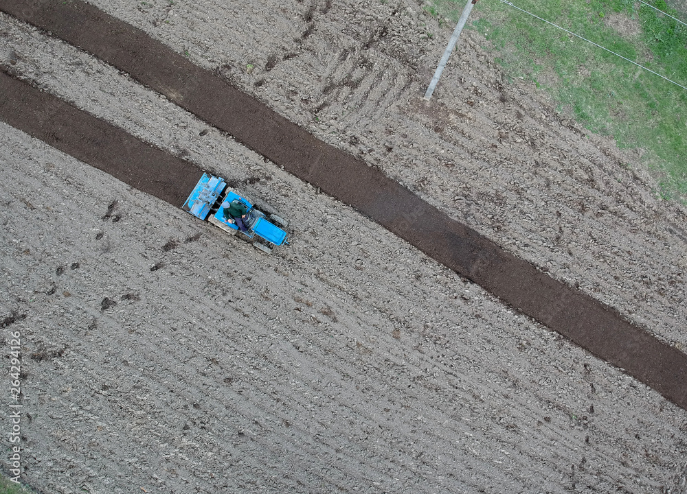 Obraz premium small tractor ploughing in the field. aerial view, agriculture