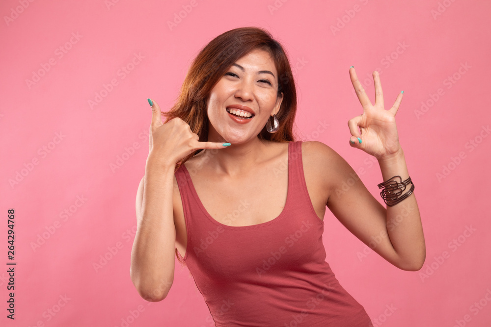 Young Asian woman show with phone gesture and OK sign. Young Asian woman show with phone gesture and OK sign.