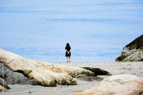 girl on shore looking out at blue ocean