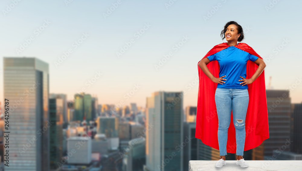 super power and people concept - happy african american young woman in superhero red cape on roof top over sunrise in tokyo city background