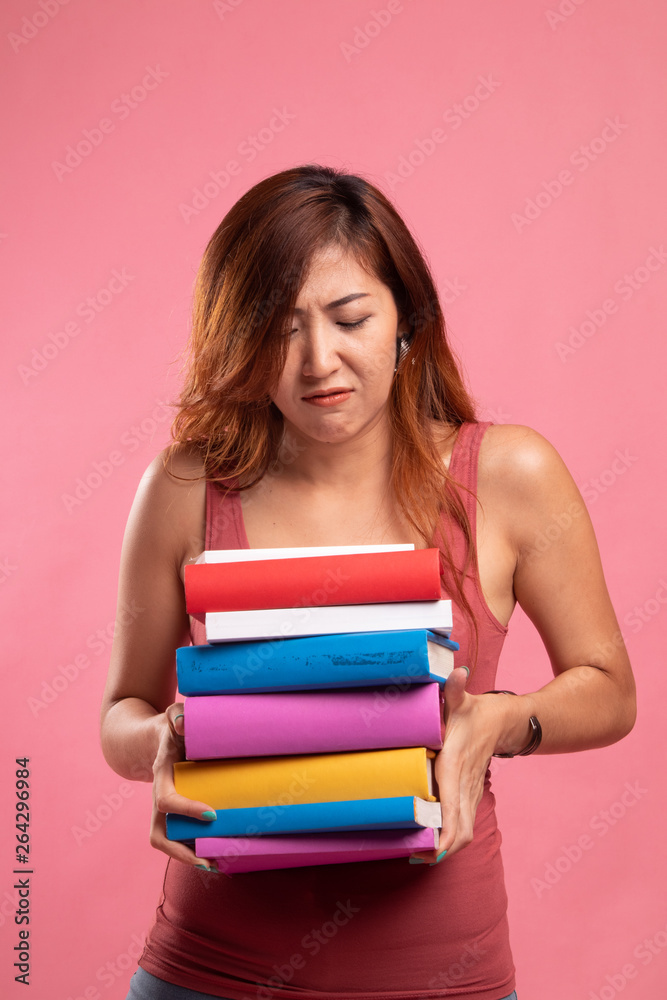 Unhappy young Asian woman studying with may books. Unhappy young Asian woman studying with may books.
