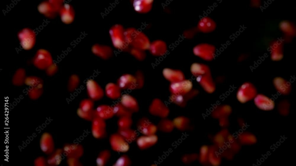 Ripe garnet grains fly to the camera on a black background in slow motion Ripe garnet grains fly to the camera on a black background in slow motion