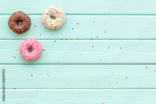 Traditional american donuts of different flavors on mint green wooden background flat lay mockup