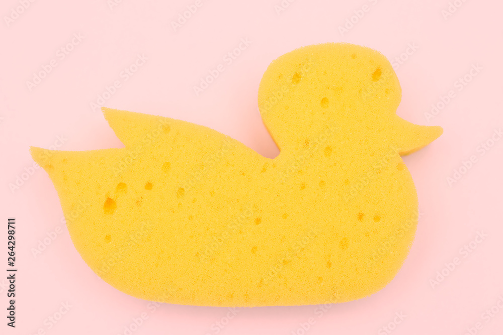 Yellow duck sponge on a pink background. view from above. baby bath sponge.