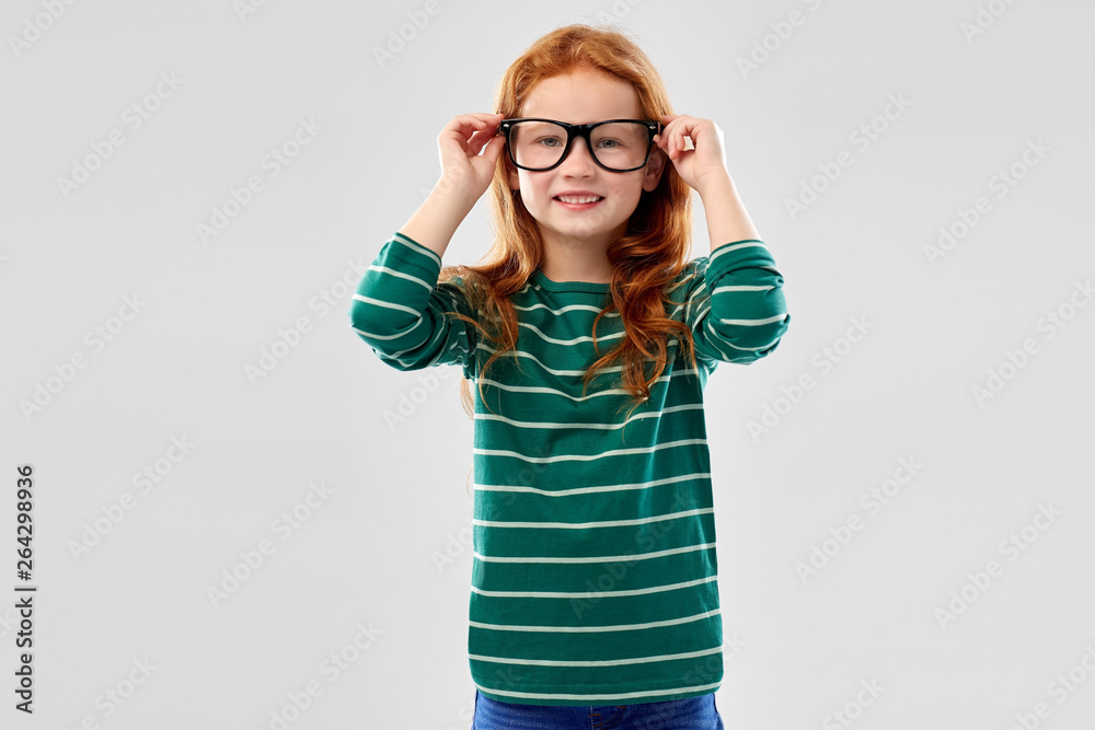 education, vision and childhood concept - smiling red haired student girl in glasses and green striped shirt over grey background education, vision and childhood concept - smiling red haired student girl in glasses and green striped shirt over grey background
