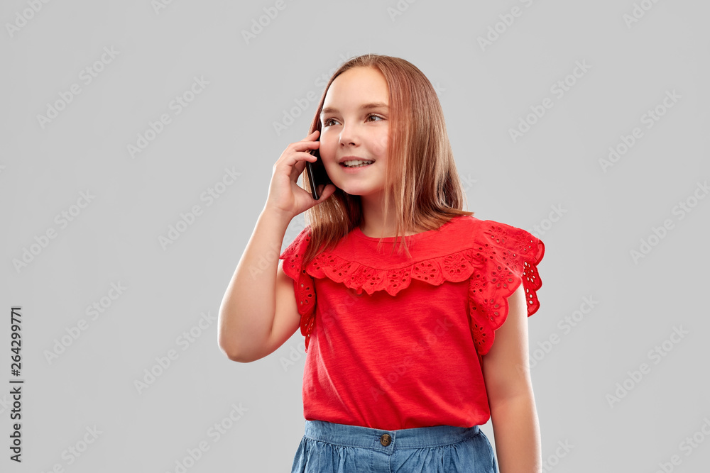 childhood and people concept - beautiful smiling girl in red shirt and skirt calling on smartphone over grey background childhood and people concept - beautiful smiling girl in red shirt and skirt calling on smartphone over grey background